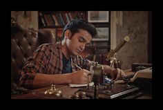 a man sitting at a desk writing on a piece of paper