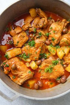 chicken stew in a pot with potatoes and garnishes on the side text reads, pollo guisado puerto rican chicken stew