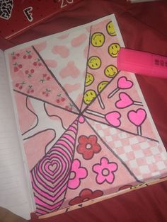 a pink notebook with smiley faces on it next to a pen and some other items