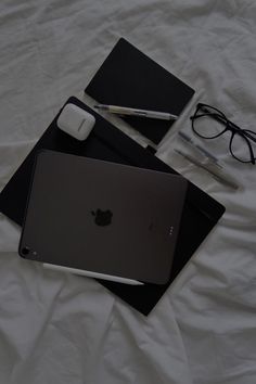 an apple laptop computer sitting on top of a bed next to a pair of glasses