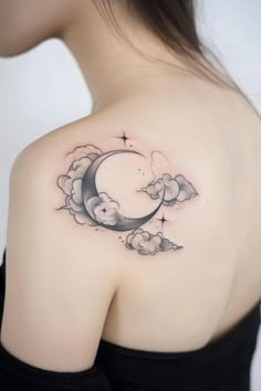 a woman's shoulder with clouds and a crescent tattoo