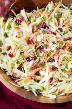 a salad with apples, cranberries, and lettuce in it on a cutting board