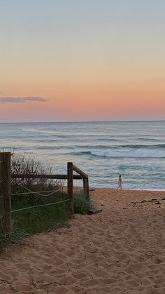 a person is walking on the beach at sunset