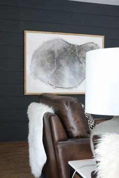 a living room with a chair, lamp and painting on the wall