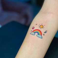 a person with a rainbow tattoo on their arm and the sun above them is in the sky