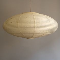 a large white paper lantern hanging from a ceiling fixture in a room with gray walls