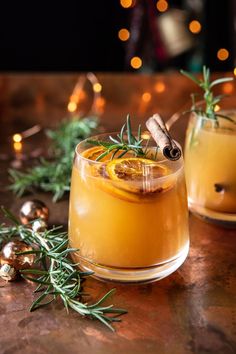 two glasses filled with drinks sitting on top of a table next to christmas decorations and lights