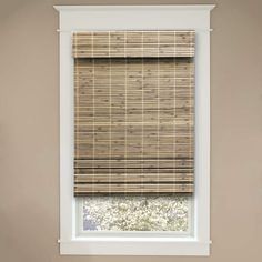 a bathroom window with a bamboo blind in the corner, and a toilet on the other side