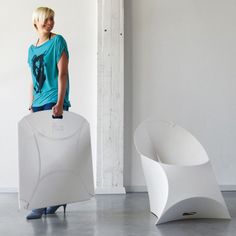 a woman standing next to two white chairs