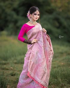 a woman in a pink sari poses for the camera with her hands on her hips