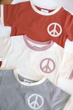 Not your basic everyday ringer tee, this retro-inspired shirt is a staple for any kiddo's collection. Chainstitch embroidered with a peace sign on the left chest, this lightweight and cozy neutral is perfect for all seasons.Here are some fun facts: Made with super soft 100% organic cotton fabric These run true to size. If your kiddo is usually a youth small, go ahead and order the size 6. if they're closer to the youth medium, a size 7 should be just right. Pre-shrunk for easy laundering individ Sweater Skirt Set, Pajama Dress, Kids Seating, Ringer Tee, Resort Collection, Socks And Tights, Organic Cotton Fabric, Children In Need, Kids Storage