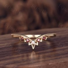 a gold ring with red stones on top of a wooden table next to a brown background