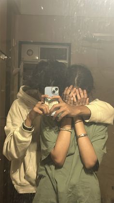 two people are hugging each other while taking a selfie in the reflection of a mirror