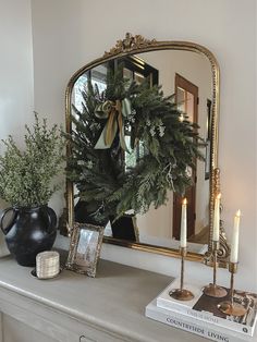 a mirror sitting on top of a mantle next to a potted plant and candle