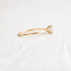 a yellow gold ring with a triangle shaped diamond in the center on a white surface