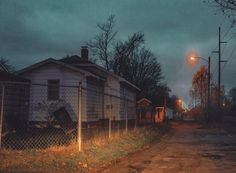 an old run down house sitting on the side of a road next to a fence