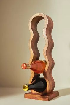 a wooden wine bottle holder with two bottles in the shape of wavy waves and a corkscrew