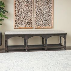 a bench sitting in the middle of a living room next to a potted plant