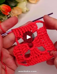 someone is crocheting a small red object with yarn and scissors in their hands