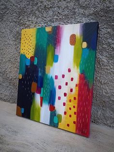 an abstract painting is displayed on the wall in front of a concrete wall and cement floor