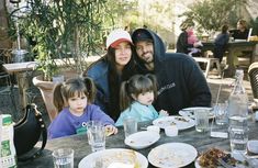 a man and two children are sitting at a table with plates of food in front of them