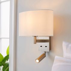 a lamp that is on the side of a wall next to a bed in a room