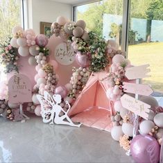 there is a pink and white tent with balloons on the wall next to other decorations