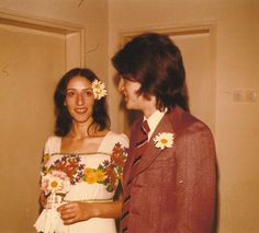 a man and woman standing next to each other in front of a door with flowers in their hair