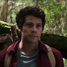 a young man holding a can of beer in the woods