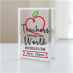 a clear acrylic with an apple on it that says teachers change the world one child at a time