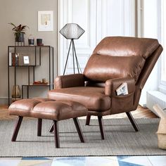 a brown leather recliner chair and ottoman in a living room with a rug on the floor