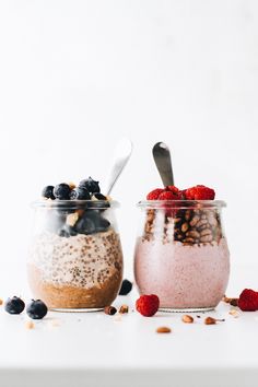 two jars filled with food sitting on top of a white table next to each other