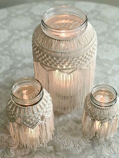 three glass jars sitting on top of a white doily covered table next to each other