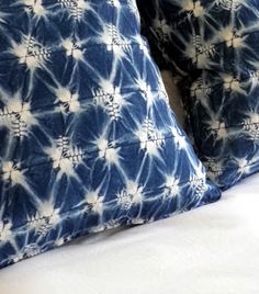 two blue and white pillows sitting on top of a bed