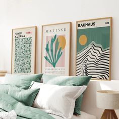 a bed with green and white pillows on top of it next to two pictures above the bed