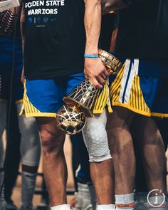 a group of men standing next to each other wearing shorts and holding basketball balls in their hands