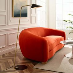 a living room with an orange couch and coffee table on the floor next to a large window