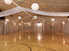 an indoor basketball court with white drapes and lights