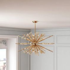 a chandelier hanging from the ceiling in a room with white walls and wood flooring