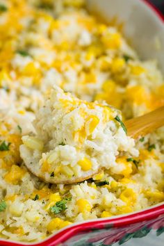 a casserole dish filled with rice and corn, topped with a wooden spoon