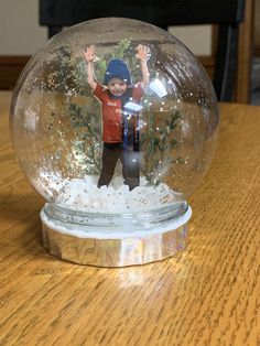 a snow globe with a boy inside on a wooden table