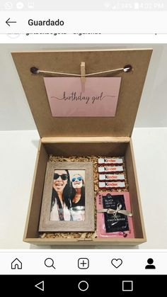 a birthday gift box with two pictures and some other items in it, sitting on a table