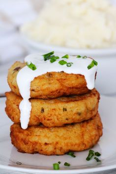 three fried chicken patties with ranch dressing and mashed potatoes in the background on a white plate