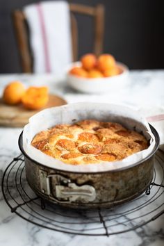 a cake sitting on top of a metal rack next to some oranges in bowls