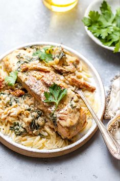 a white plate topped with pasta and meat covered in sauce, garnished with cilantro