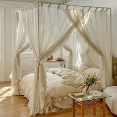 a bed with white sheets and drapes on it's headboard in a bedroom