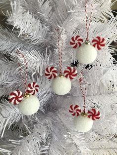 three ornaments hanging from a white christmas tree with candy canes on it's sides