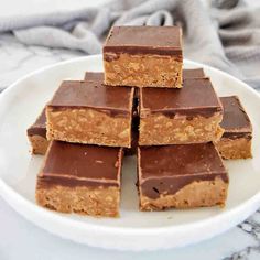 chocolate peanut butter bars stacked on top of each other in front of a white plate