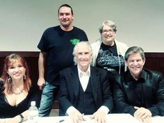 a group of people sitting at a table posing for the camera with their arms around each other