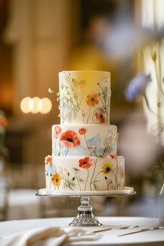 a three tiered cake with flowers painted on it